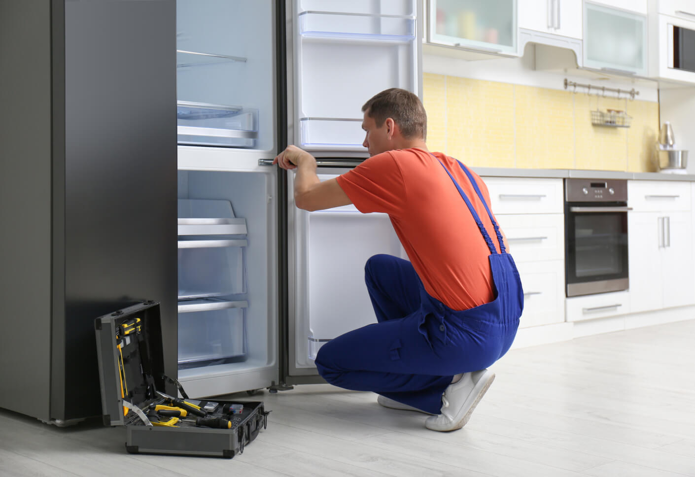 Technician working on a refrigerator drawer with an open toolkit nearby